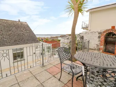 a patio with a table and a palm tree at Mount View Cottage in Marazion