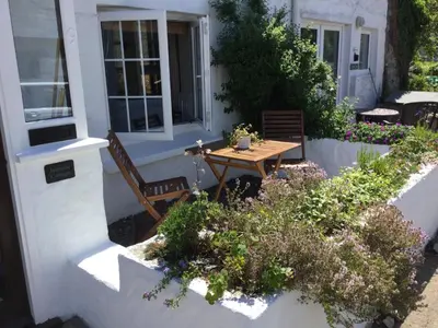 a small garden with a wooden table and some flowers at Jasmine Cottage in Lerryn