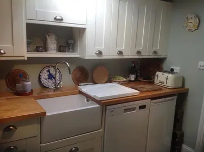 a kitchen counter with white cabinets and a sink at Jasmine Cottage in Lerryn