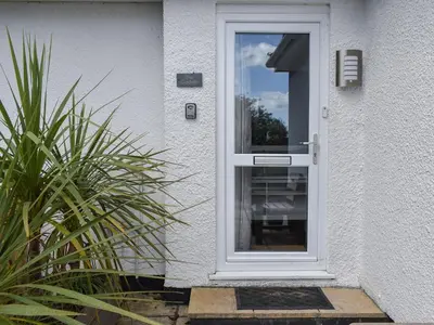 a white door on a house with a plant at Caddie - Uk11038 in Carlyon Bay