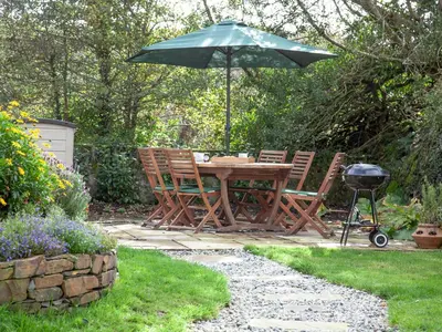 a picnic table and chairs with an umbrella in a garden at Greenbank Farm in Saint Dennis