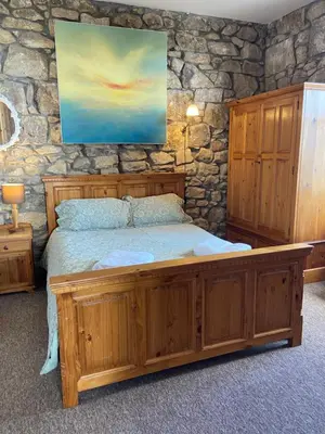 a bedroom with a large wooden bed in a stone wall at THE STONES St Ives Apartment Panoramic Harbour Views and Onsite Parking in St Ives