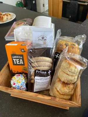 a basket of pastries and other food on a table at THE STONES St Ives Apartment Panoramic Harbour Views and Onsite Parking in St Ives