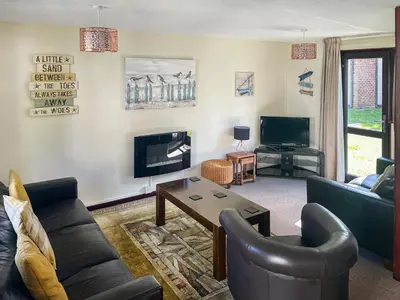 a living room with couches and a tv at Trevithick Lodge in Hayle