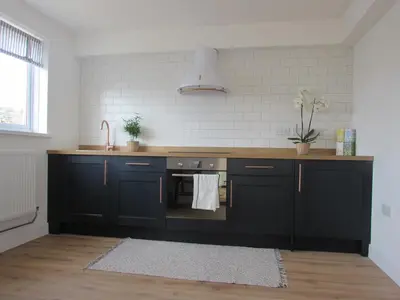 a kitchen with black cabinets and a sink at White Willows in Praa Sands