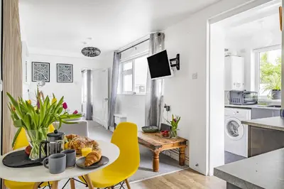 a kitchen and dining room with a table and yellow chairs at Waters Edge Holiday Home in Hayle, West Cornwall in Hayle