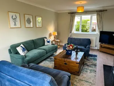 a living room with two blue couches and a coffee table at Hendra Holiday Park in Newquay