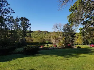 a green yard with trees and bushes and a field at Great Trethew Manor Hotel & Restaurant in Menheniot