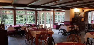 a dining room with tables and chairs and windows at Great Trethew Manor Hotel & Restaurant in Menheniot