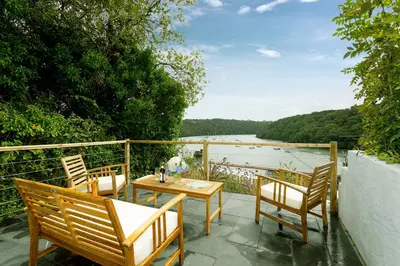 a patio with a table and chairs and a view of a lake at Fal River Cottage in Truro