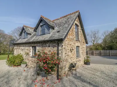 an old brick house with flowers in a yard at The Coach House in Saint Columb Major