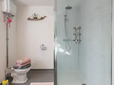 a bathroom with a glass shower with a toilet at Be Our Guest Cottage in Truro