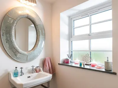 a bathroom with a mirror and a sink at Be Our Guest Cottage in Truro