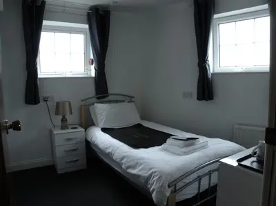 a bedroom with a bed and two windows at Elnor Guest House in Liskeard