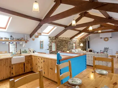 a kitchen with wooden cabinets and a table and chairs at New England-Uk12750 in Menheniot