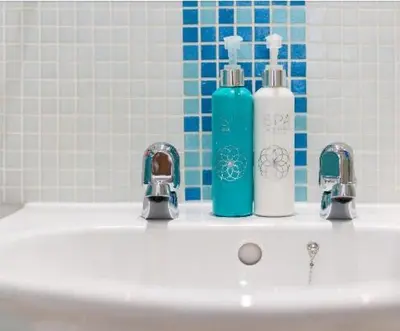 a bathroom sink with two soap bottles and two faucets at Tredara Bed & Breakfast in Truro