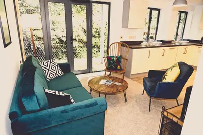 a living room with a couch and chairs and a table at Fowey Landing in Fowey