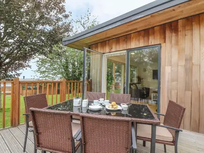 a patio with a table and chairs on a deck at Ash in Truro