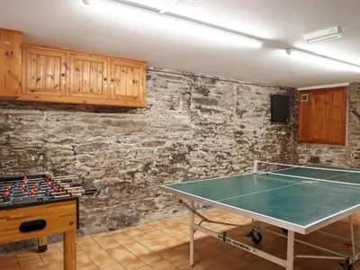 a ping pong table in a room with a stone wall at Lower Deck in Fowey