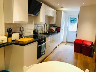 a kitchen with white cabinets and a black counter top at Beach Road- short walk to Charlestown, Carlyon Bay & coastal paths- dog friendly in Carlyon Bay