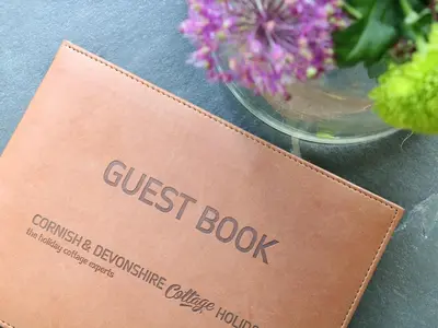 a guest book sitting next to a vase of flowers at Ash Cottage in Truro