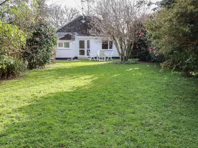 a small white house with a lawn in front of it at 5 Carlyon Road in Truro