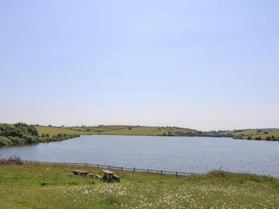 a lake with two picnic tables in front of it at Little Hamlin in Callington