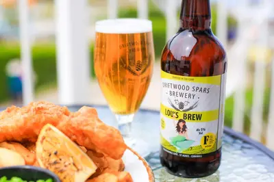 a bottle of beer next to a plate of food at Driftwood Spars in St. Agnes