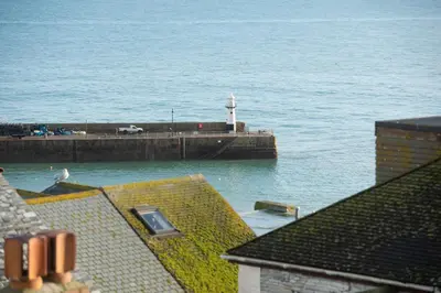 a pier with a lighthouse in the water at Waves Apartment, St Ives in St Ives