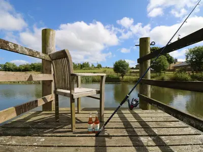 a chair and two bottles of beer on a dock at Elm Cottage in Truro