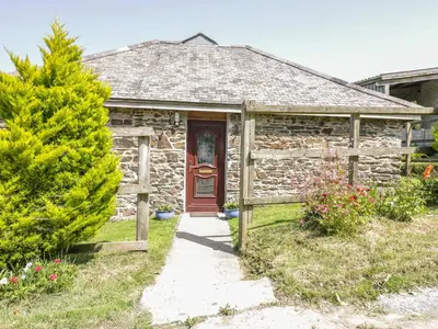 a stone cottage with a red door and a tree at Garras Barn in Truro