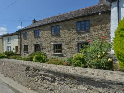 an old stone house with a garden in front of it at Samuels Cottage in Lanreath