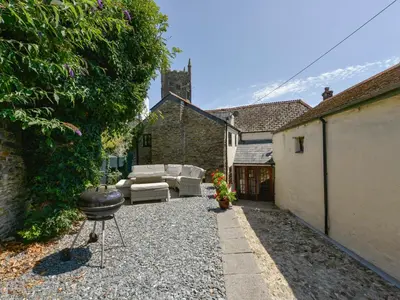 a backyard with a grill and a couch and a fire place at Samuels Cottage in Lanreath