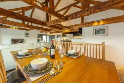a kitchen and dining room with a wooden table at Copperhouse View in Hayle