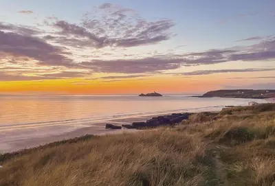 a view of a beach at sunset with the ocean at Copperhouse View in Hayle