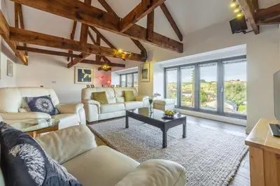 a living room with white furniture and large windows at Copperhouse View in Hayle