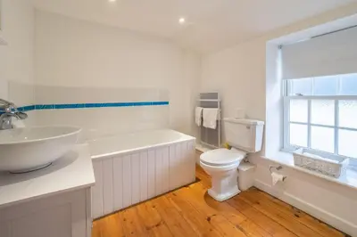 a white bathroom with a toilet and a sink at Balwest Cottage in Helston