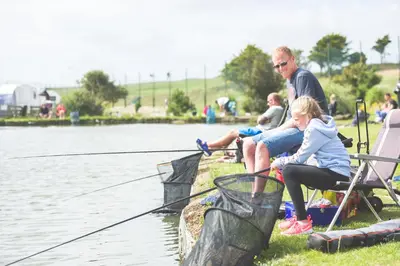 a man and a little girl sitting next to the water at Popham Cottage in Cornwall in Newquay