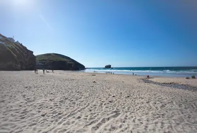 a beach with people walking on the sand and the ocean at Westaway in Portreath
