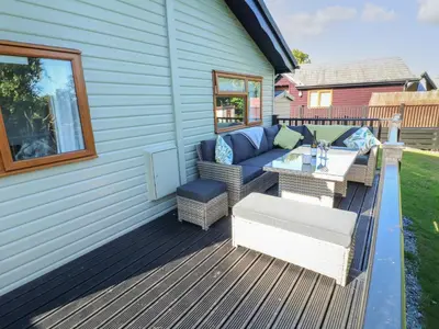 a patio with a couch and a table on a deck at Smugglers Shack in Polperro
