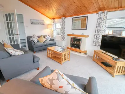 a living room with couches and a tv and a fireplace at Smugglers Shack in Polperro