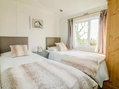 two beds in a room with a window at Smugglers Shack in Polperro