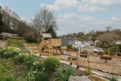 a wooden playground in a garden with flowers at Compass Point in Falmouth