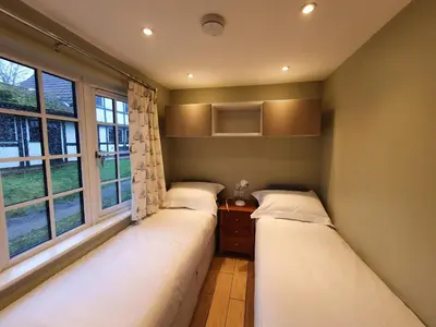 two beds in a room with two windows at 41 Tudor Court in Hayle