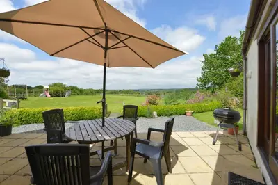 a table and chairs with an umbrella on a patio at Valley View in Helston