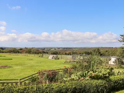 a garden with a fence and a field at Valley View in Helston