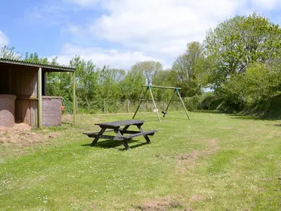 a picnic table and swing set in a field at Linhay - Ukc4242 in Lanreath