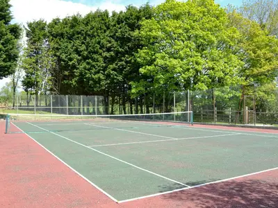 a tennis court with a net and some trees at Holly - Ukc4243 in Lanreath