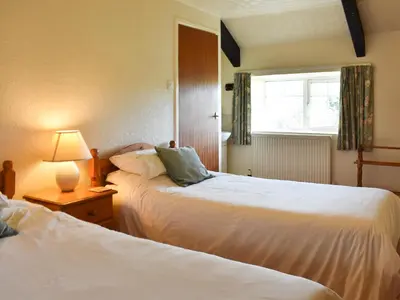 a bedroom with two beds and a window and a lamp at Hayloft - Ukc4241 in Lanreath