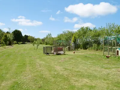a field with chickens and a cage in the grass at Hayloft - Ukc4241 in Lanreath